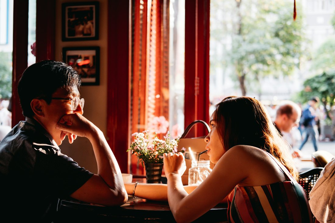 Two people deep in conversation at a café table in afternoon light