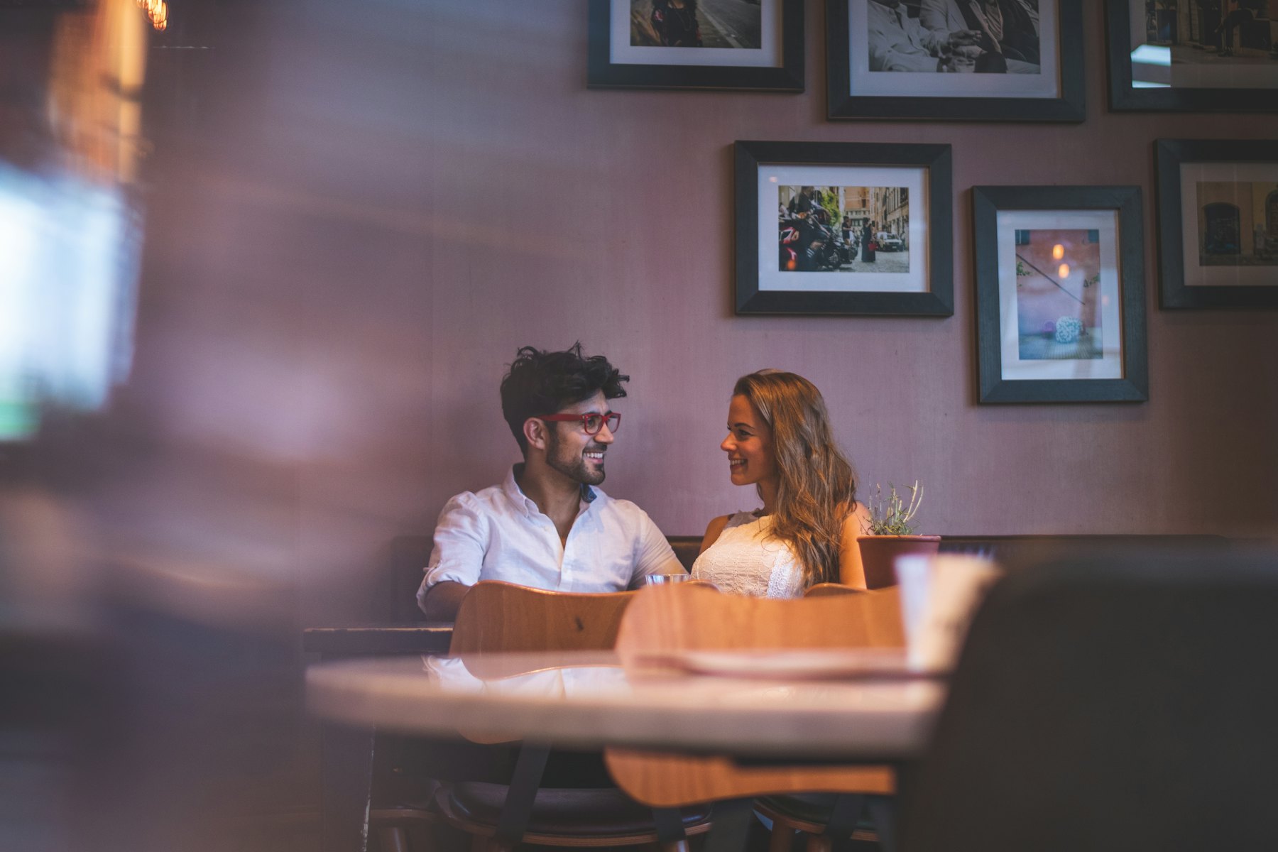 Two people talking across a table in a warm, low-lit bar